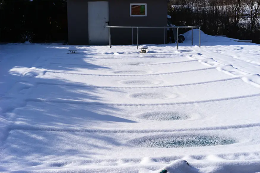 Schneebedeckte Poolabdeckung auf einem Gartenpool im Winter