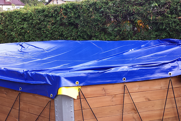 gpsave_poolabdeckung_flach_600x400 Blaue PVC-Poolplane mit Ösen und Spanngummis auf einem Aufstellpool