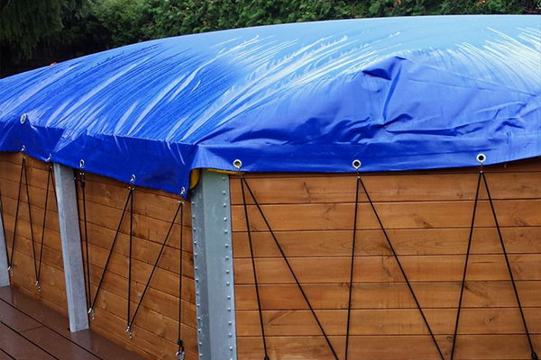 gpsave_poolabdeckung_spanngummi_600x400 Blaue Poolplane mit Metallösen und Spanngummis an einem Holzpool